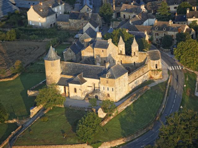 Vue aérienne du château d'Onet-le-Château : son mur d'enceinte et ses tourelles, à côté du village