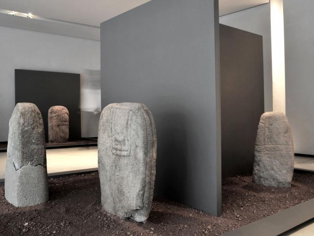 Quatre statues-menhirs dans la terre, dans une salle du musée Fenaille de Rodez