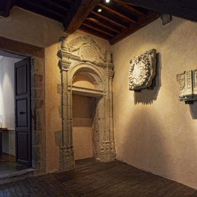 Salle du Musée Fenaille avec parquet ancien en bois au sol et sculptures en pierre aux murs