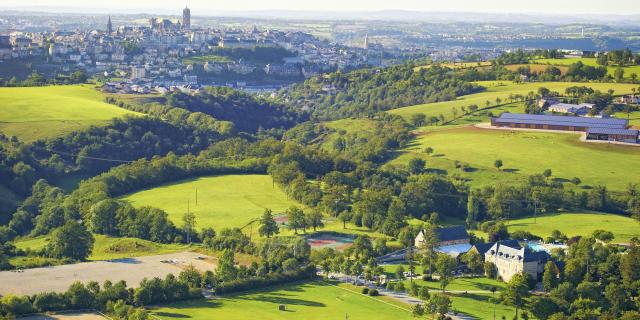 Vue aérienne du Domaine de Combelles, avec ses prés et ses terrains de tennis, avec Rodez en arrière-plan