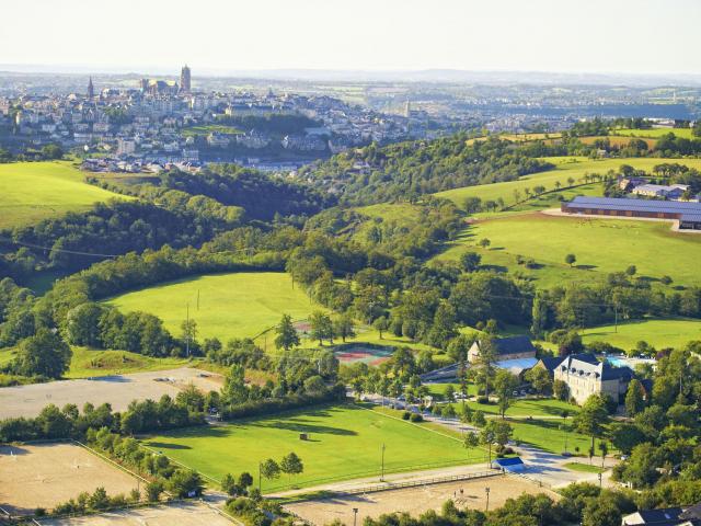 Vue aérienne du Domaine de Combelles, avec ses prés et ses terrains de tennis, avec Rodez en arrière-plan