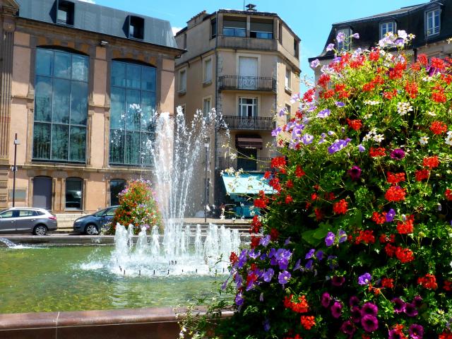 Place de la mairie à Rodez avec sa fontaine et ses compositions florales, au milieu de bâtiments imposants