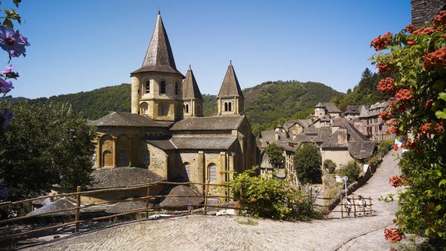 Au bord d'un chemin pavé, abbaye Cistercienne au cœur du village typique de Conques