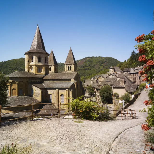 Au bord d'un chemin pavé, abbaye Cistercienne au cœur du village typique de Conques