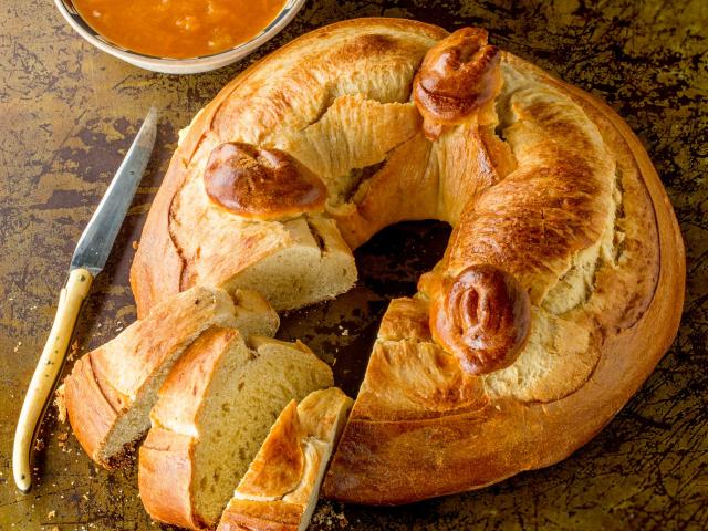 Gâteau de fouace avec trois parts tranchées, à côté d'un couteau Laguiole et d'un bol de confiture