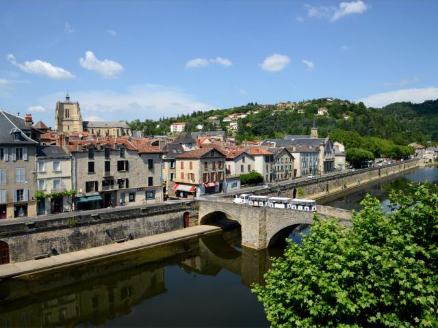 Chartreuse, maisons et ville de Villefranche de Rouergue au bord de la rivière Aveyron avec un pont où passe un petit train touristique