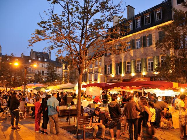 Foule de personnes présentes au marché gourmand nocturne de l'été, sur une place historique de Rodez