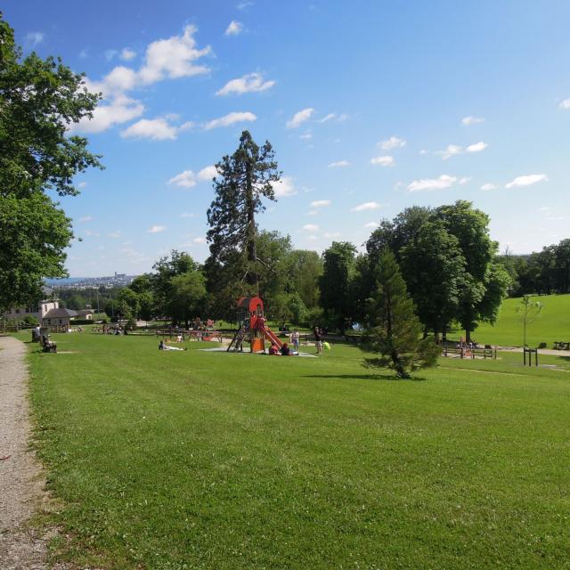 Personnes se délassant au soleil sur la pelouse tout surveillant leurs enfants en train de jouer aux jeux en bois du Domaine de Vabre