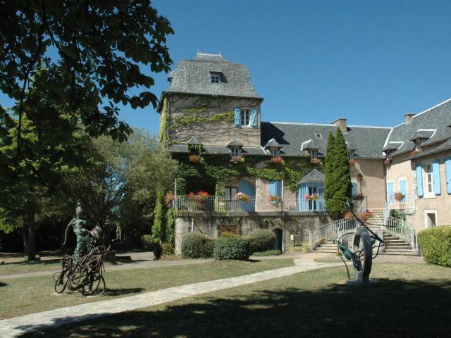 Sculpures en fer dans le parc devant la mairie de Sébazac-Concourès aux murs avec du lierre et des volets bleu