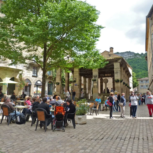 Place devant les halles en pierres de Saint Antonin Nobleval, personnes assises en terrasses de café