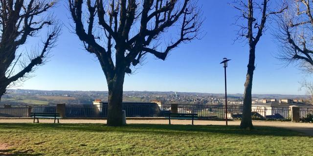 Vue sur Rodez et Olemps depuis le square Fabié où il y a des bancs, une promenade et des arbres nus