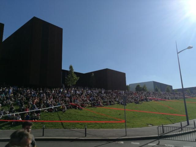 Foule assise au soleil devant le musée Soulages, au bord de rubalises installées à l'occasion de la Spéciale à Rodez du Rallye du Rouergue