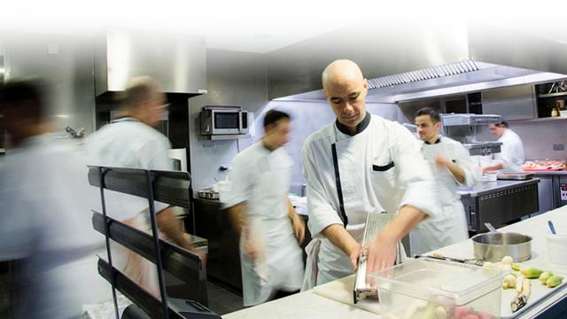 Chef Chaillou en tablier blanc s'affairant dans sa cuisine, en centre de son équipe en mouvement