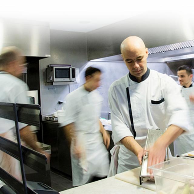 Chef Chaillou en tablier blanc s'affairant dans sa cuisine, en centre de son équipe en mouvement