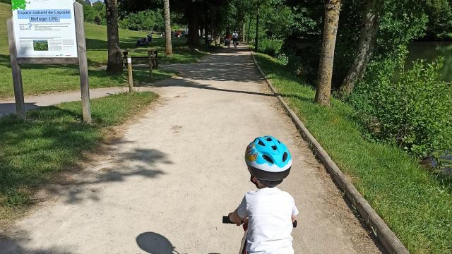 Enfant sur une draisienne sur un chemin à l'entrée du site de Layoule au bord de la rivière Aveyron