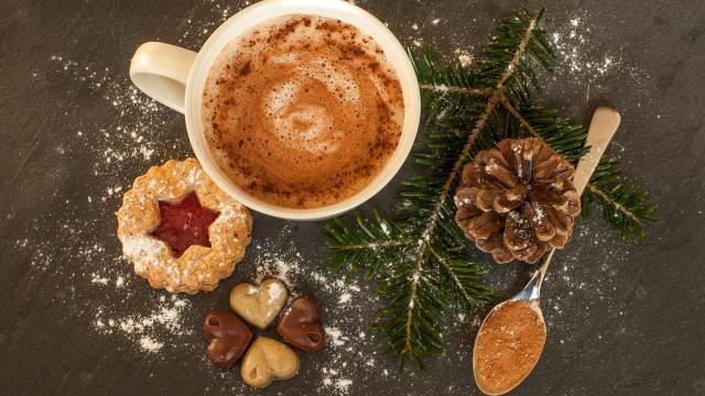 Chocolat chaud, gâteau sec et chocolats en forme de cœur, avec une décoration de branche de sapin et pomme de pin