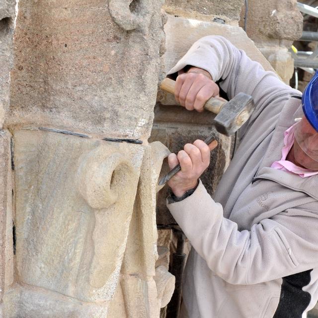 Ouvrier casqué qui taille la pierre de la cathédrale à l'aide d'un marteau et d'un burin