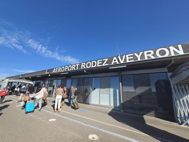 Personnes avec leur valise à roulette et leur sac à dos à l'aéroport Rodez Aveyron