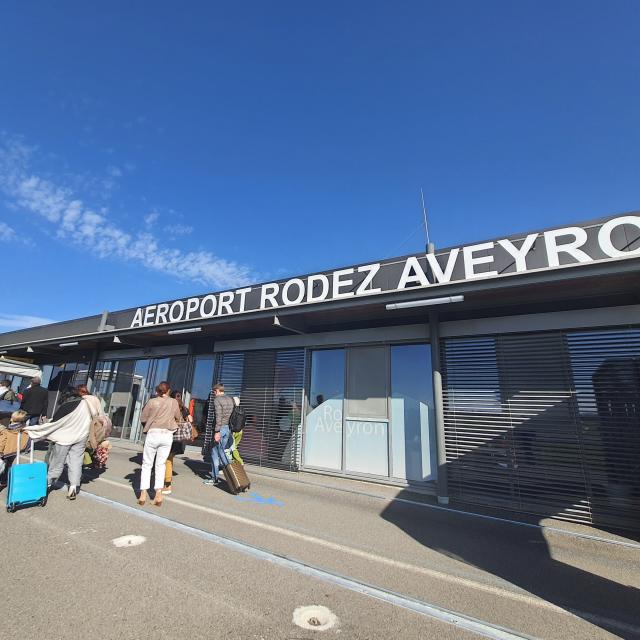 Personnes avec leur valise à roulette et leur sac à dos à l'aéroport Rodez Aveyron