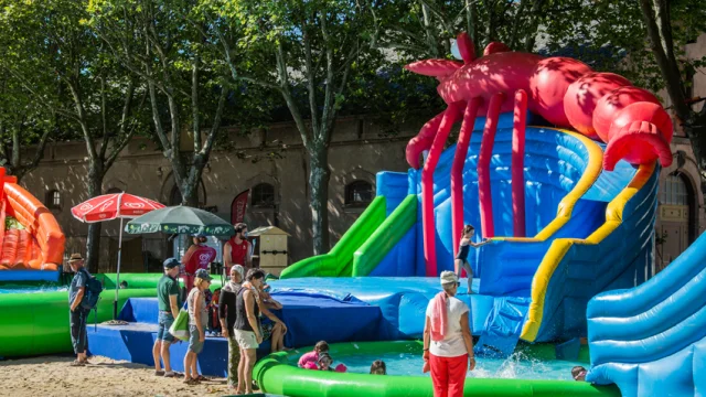 Parents devant des jeux gonflables et des jeux d'eau où s'amusent leurs enfants