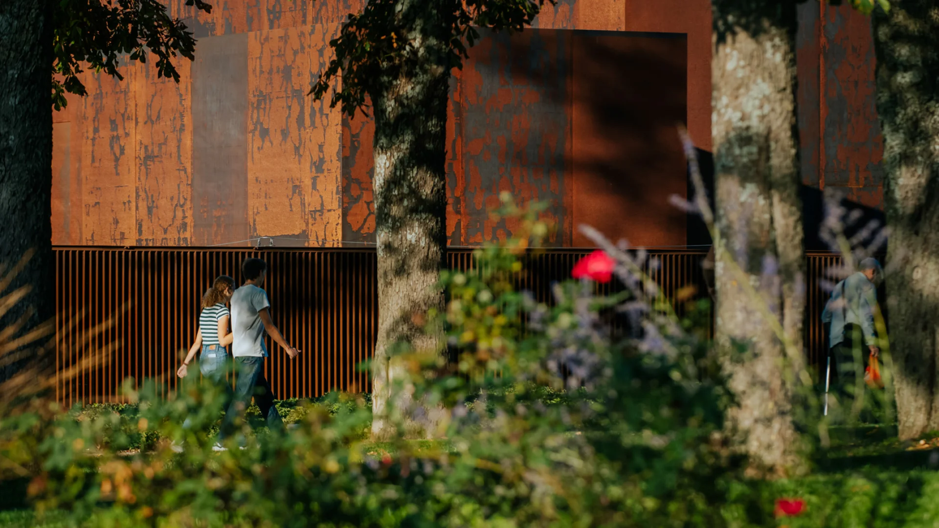 Couple se promenant dans le jardin du Foirail, bordant le musée Soulages et son bardage en Acier Corten couleur rouille